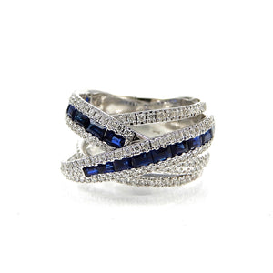 Multiple white gold bands of diamonds and baguette blue sapphires create one geometric band style ring