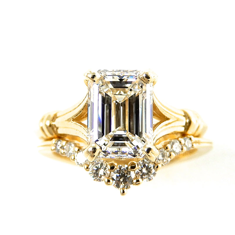 Gold plit shank ring with a emerald cut diamond and smaller round diamonds on the 