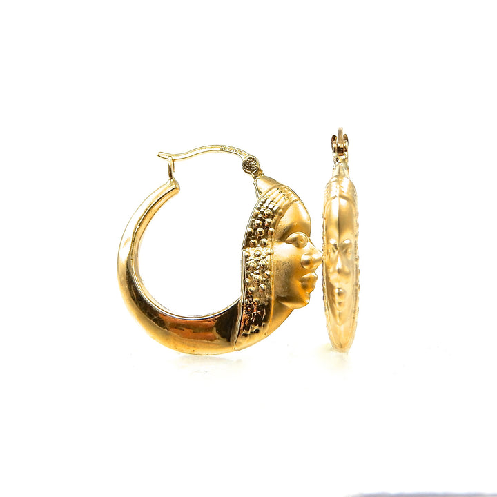 Gold hoop earrings with face design on a white background