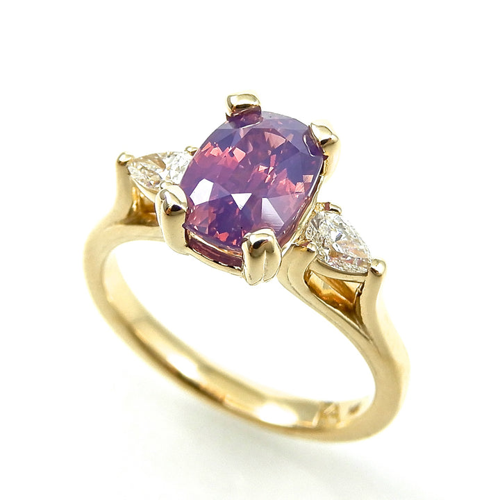 opalescent oval cut sapphire with two pear shaped diamond side stones set in yellow gold