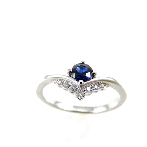 "v" shape white gold band with single blue sapphire and crown style round diamond accents