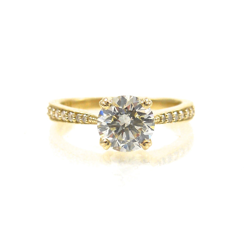 solitaire engagement ring featuring a 4 prong set center stone accented with diamonds in yellow gold