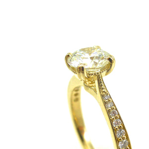 solitaire engagement ring featuring a 4 prong set center stone accented with diamonds in yellow gold