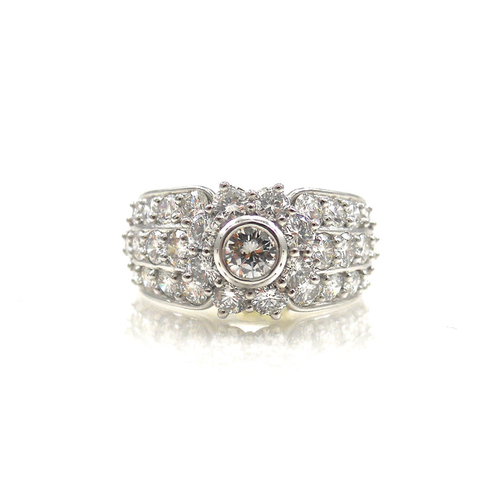  bezel-set diamond center stone surrounded by a diamond halo in a pave diamond wide shank ring