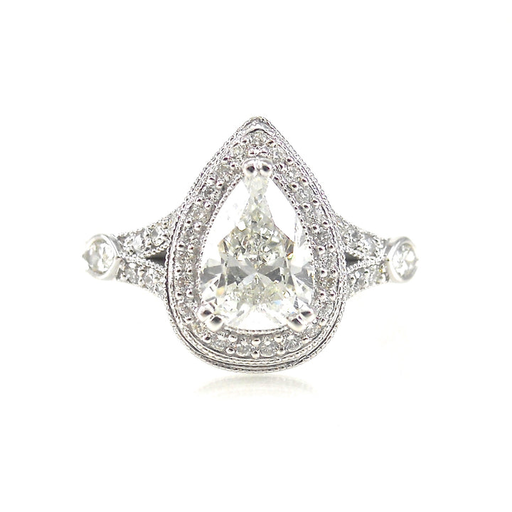  halo engagement ring featuring a pear shaped center stone with round brilliant diamond and milgrain accents
