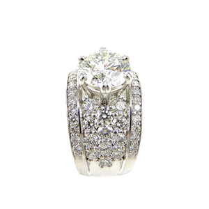 round brilliant cut diamond center stone ring with a pave diamond accented shank and diamond borders