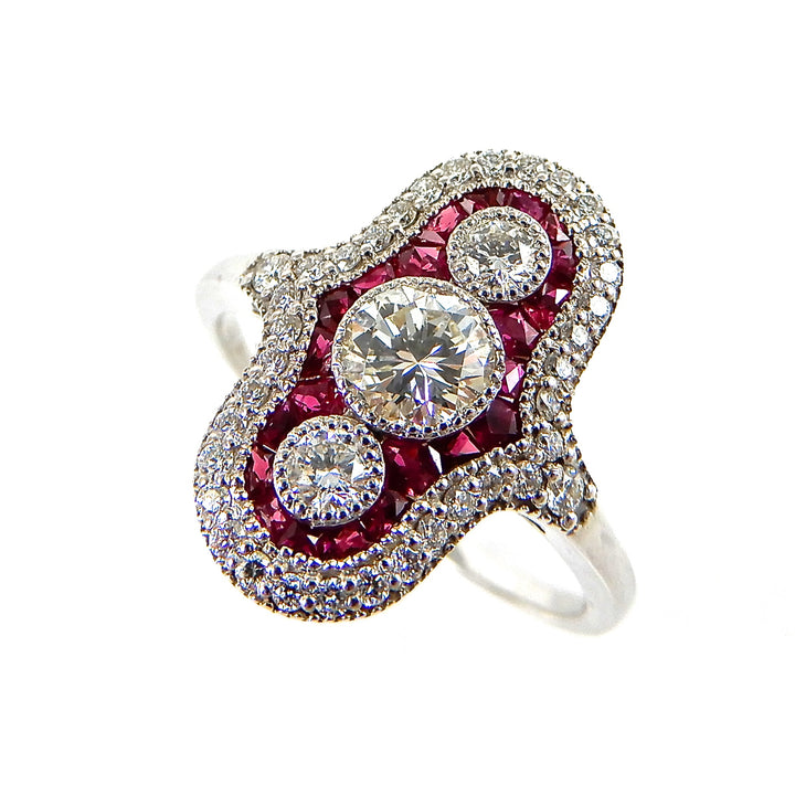 Vintage inspired cockatil ring with three round diamonds surrounded by rubies and an elongated diamond halo in white gold