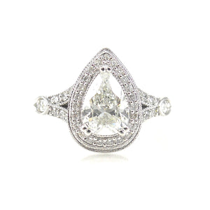  halo engagement ring featuring a pear shaped center stone with round brilliant diamond and milgrain accents